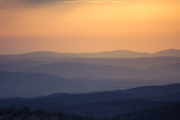 Orange and yellow sunset with mountains silhouettes. Gradient vivid nature background.