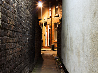 Looking down a dark empty back alleyway at night