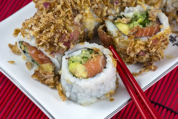 Sushi with salmon and red chopsticks on the red bamboo mat
