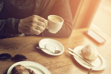 Fototapeta na wymiar Coffee time. Man drinking cappuccino in morning cafe, image tone