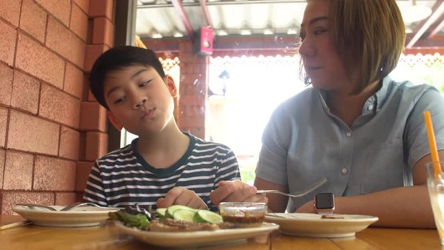 Happy Asian mother with her son eating lunch at home,happy asian family enjoy with meal