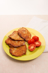 Potato pancakes with meat and tomatoes on green plate in Belarus