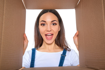 Happy girl opening postal package. Excited young woman holding c