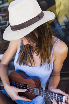 Smiling girl in hat playing music using ukelele