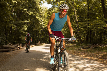 Fototapeta premium Two mountain bikers riding bike in the forest on dirt road.