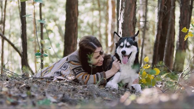 Portrait of eye-catching girl lying in the forest with her dog
