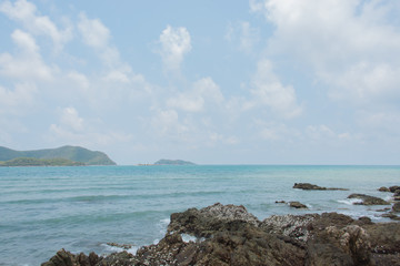 Sea waves crashing over rocks on wild stone beach , Thailand. Calm sea water,  Sattahip. White clouds on a blue sky over summer sea with sunlight reflection, Sattahip tropical sea relax