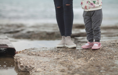 Close-up of mother and baby feet. woman and baby feet walking on sand beach for first time.