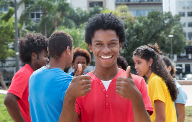 Young african american man with friends showing both thumbs