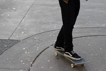 Young man riding his skateboard on gum stained concrete roadway