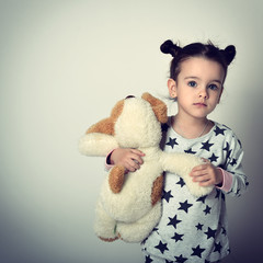 Little lovely sleepless girl in pajamas holding her loved plush