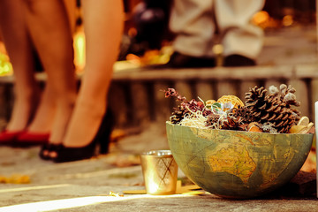 Golden glass for a candle stands behind the bowl made of globe
