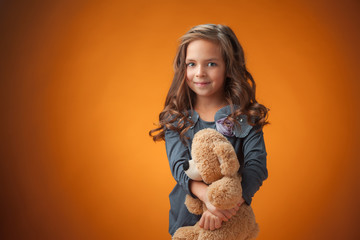 The cute cheerful little girl on orange background