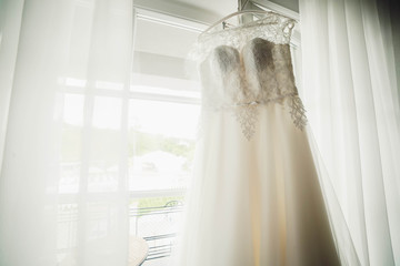 beautiful dress for the bride hanging on the cornice