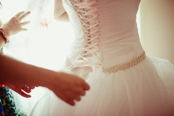 Lady laces up a corset on a thin bride