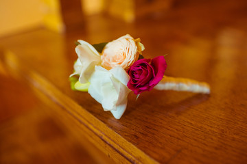 Little white boutonniere lies on the wooden table