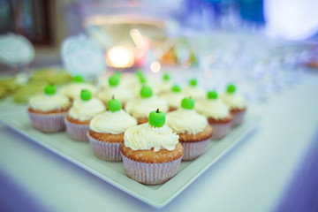 Pretty cupcakes with white cream and green apples stand on the s