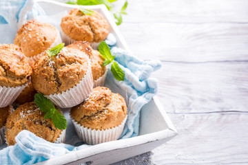 Delicious homemade coconut cinnamon muffins and mint leafs on old white tray. Healthy food concept with copy space. - obrazy, fototapety, plakaty
