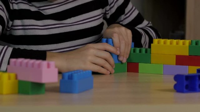 little boy playing in the colored blocks sitting at the table