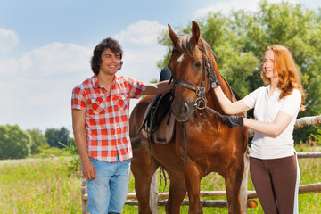 Obraz premium Happy young people walking with their bay horse