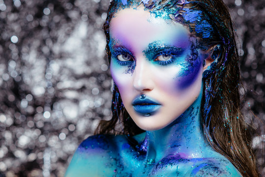 Portrait of a beautiful mermaid girl. Wet skin, wet hair, glitter and scales on his face. Blue eyes. The image on Halloween. Advertising Space.