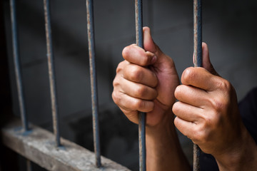 Soft focus on hands of man behind jail bars. vintage or retro style. selective focus.