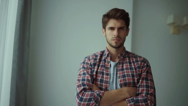 Happy young man. Portrait of handsome young man in casual shirt keeping arms crossed and smiling while standing against grey background