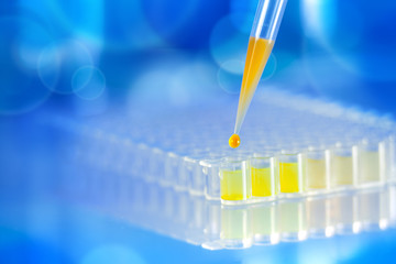 Laboratory pipette with a drop of substance over test tubes