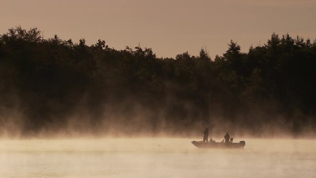 Two fishermen on boat in foggy lake