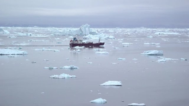ship driving between big icebergs on arctic ocean