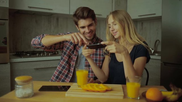 Funny couple taking pictures of tasty oranges.