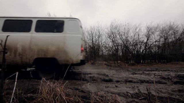 Countryside. Russian Vehicle Moving Through the Mud on the Road. Leafless Trees on the Side. Late Autumn. Heavy Grey Sky