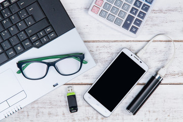 Top view of laptop, calculator, glasses, smartphone and USB flas