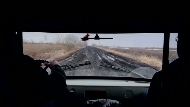 Riding a Car on a Bumpy Road. 2 Men Inside the Vehicle Riding, Swaying, Jumping. Muddy Road. Dark Cabin. Countryside. Late Autumn. Rear Seat View