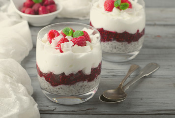 Healthy breakfast, desert, with chia seed pudding, cream, raspberry jam, coconut flakes and fresh berries