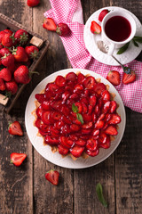 Tart with strawberries and whipped cream on wooden background