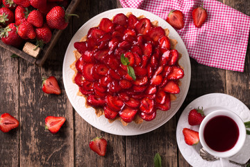 Tart with strawberries and whipped cream on wooden background