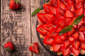 Tart with strawberries and whipped cream on wooden background