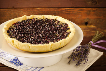 Bilberry, blueberry tart with lavender on white plate, wooden background