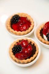  mini cherry pies/tarts on  plates garnished with blackberry