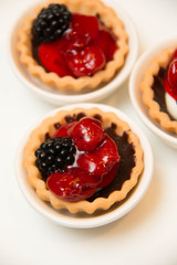  mini cherry pies/tarts on  plates garnished with blackberry