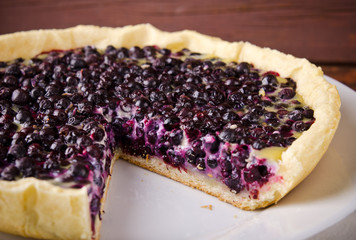 Bilberry, blueberry tart with lavender on white plate, wooden background