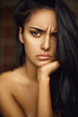 Obraz premium Closeup beauty portrait of a frowning brunette girl with long hair.