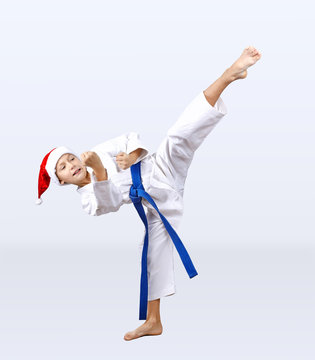 Boy in karategi and hat of Santa Claus hits a kick