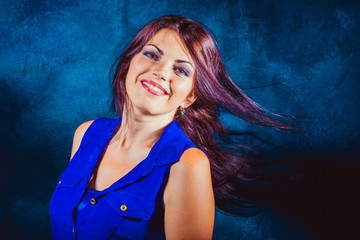 Woman in blue dress shakes her long dark hair