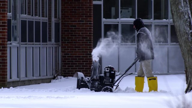 Slow motion of a man using snow blower in deep snow