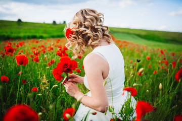 Look from behind at a blonde woman walking through the field of