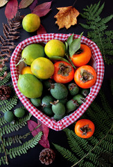 Фрукты в корзине: хурма, лимоны, фейхоа с осенними листьями