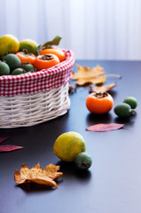Фрукты в корзине: хурма, лимоны, фейхоа с осенними листьями