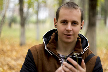 Young man listening to music on smartphone on the nature